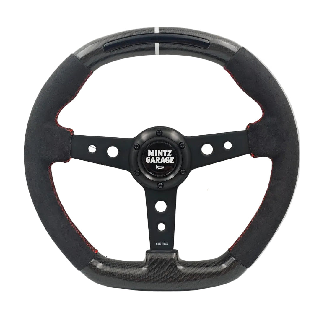 A black carbon fiber and suede racing steering wheel with red stitching, featuring a central black hub with the 'MINTZ GARAGE' logo and visible wiring on a white background.